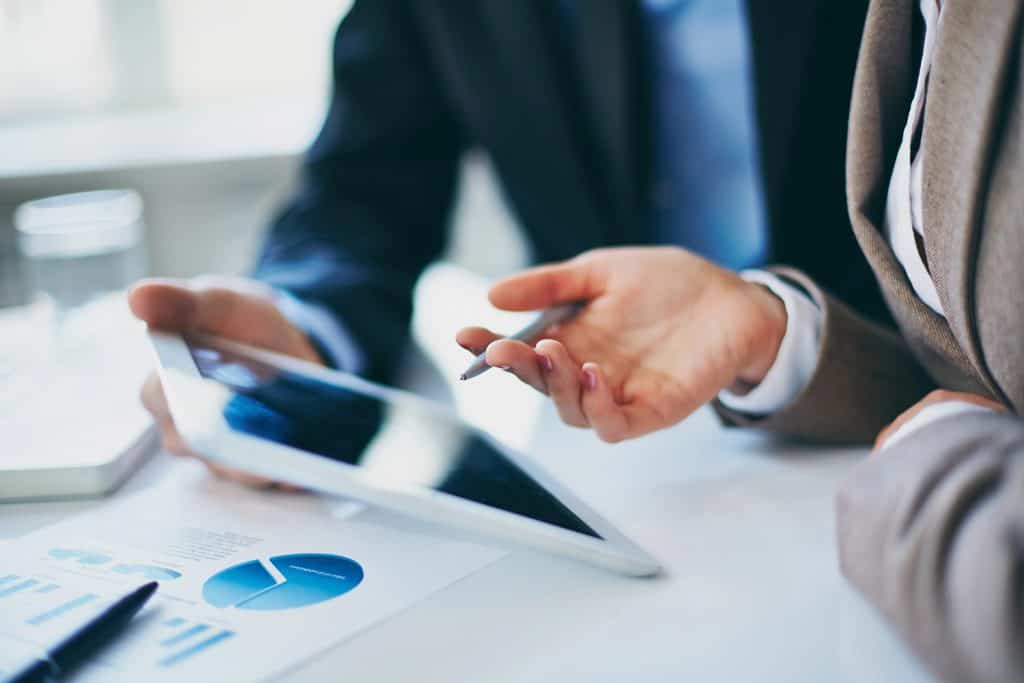 Business people using their AV setup, including a tablet to look at financial data.