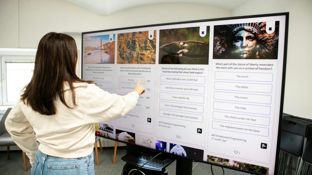 Person using a large touchscreen interactive display, representing the rise of AV technology in modern UK corporate environments.