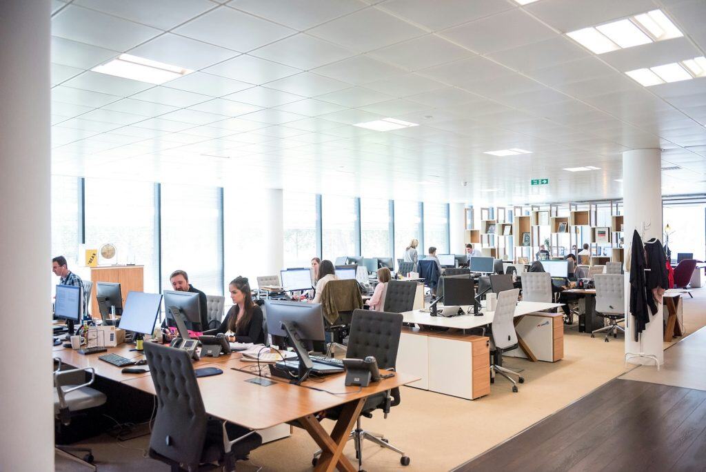 Modern open-plan office with employees working at desks, illustrating the importance of reliable internet for business operations.