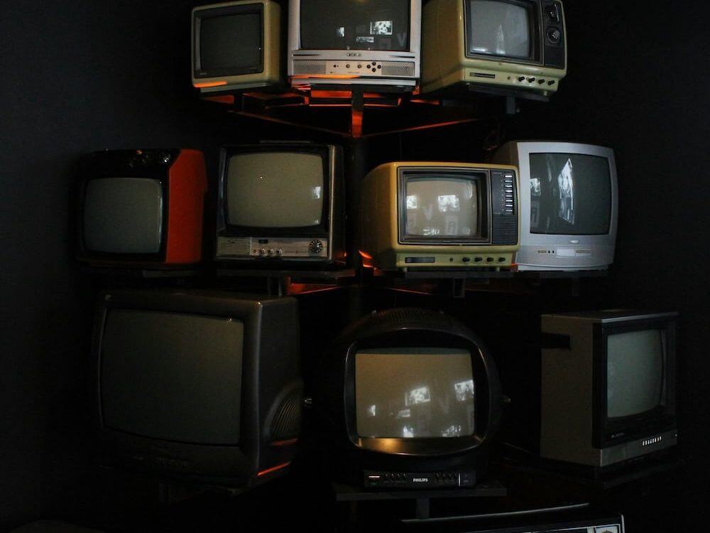 Stack of vintage televisions representing the evolution of audiovisual technology leading to modern commercial AV trends in 2025.
